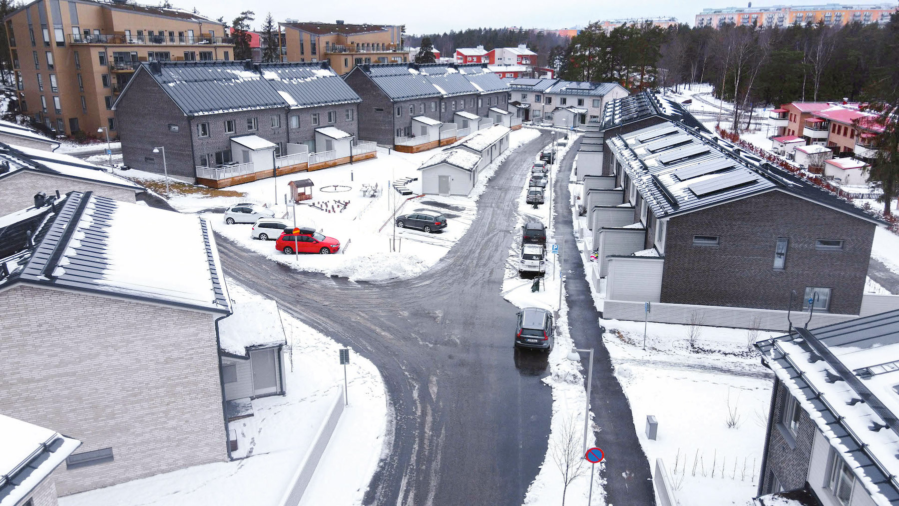 Radhusområde i vintermiljö med snö och parkerade bilar.
